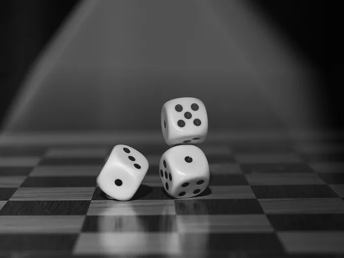 Three white dice on a reflective checkered surface